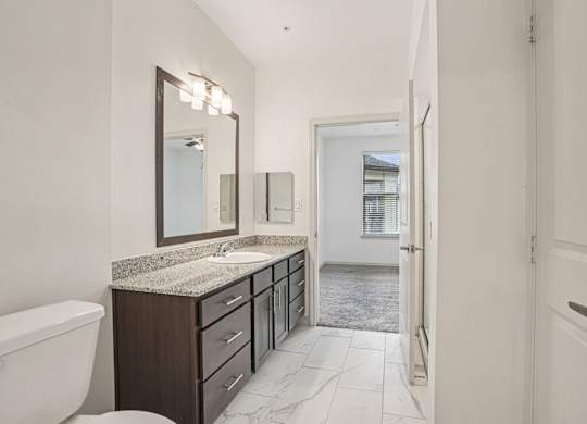 A bathroom with a white toilet, sink, and vanity.