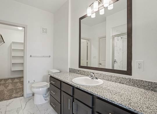 A bathroom with a toilet, sink, and mirror.