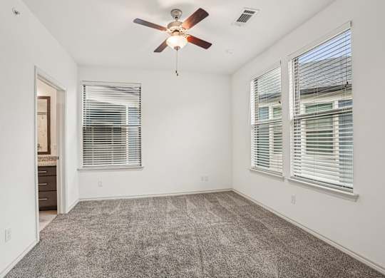A room with a ceiling fan and carpeted floor.