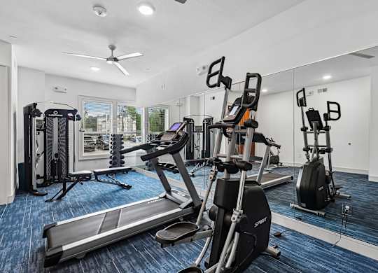 A gym with a treadmill, elliptical machines, and other exercise equipment.