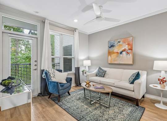 A living room with a blue chair, a white couch, and a painting on the wall.