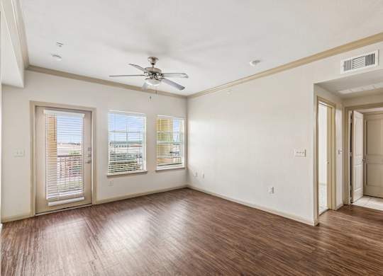 A room with a ceiling fan and wooden floors.