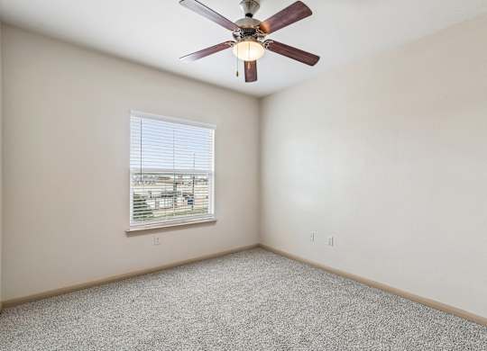 A room with a ceiling fan and a window with blinds.