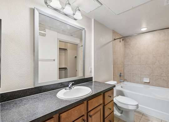 A bathroom with a sink, mirror, toilet, and bathtub.