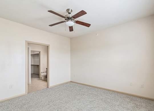 A room with a ceiling fan and carpeted floor.