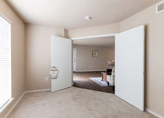 A room with a white door open to a living room.