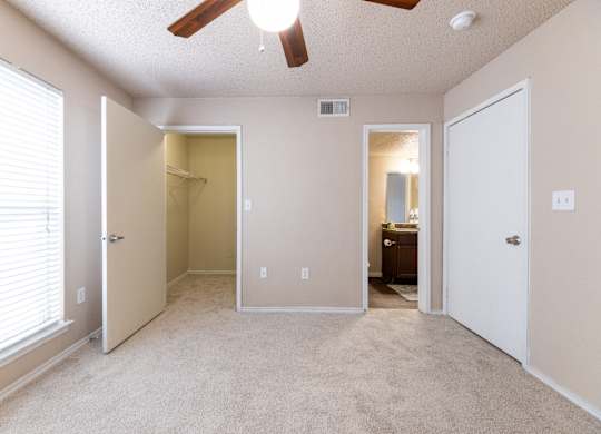 A room with a ceiling fan and a window with blinds.