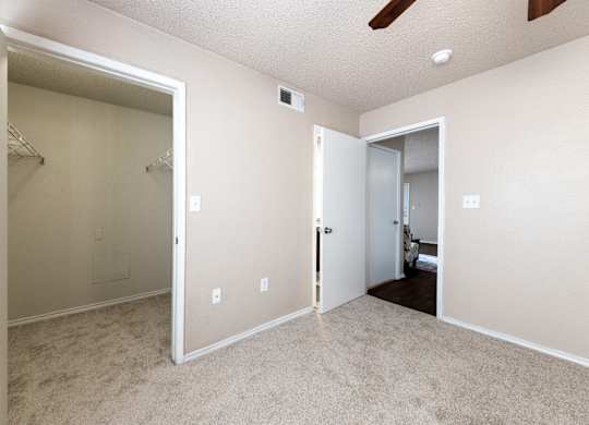 A room with a carpeted floor and a ceiling fan.