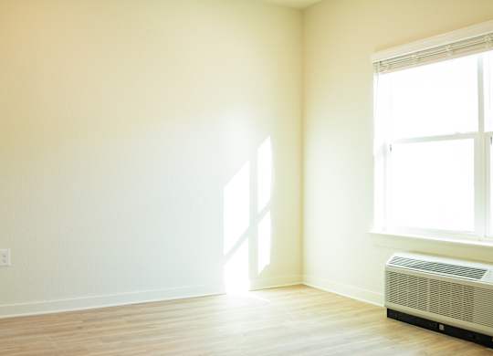 A room with a window and a wall-mounted air conditioner.