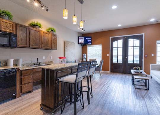 A kitchen with wooden cabinets and a bar area with stools.