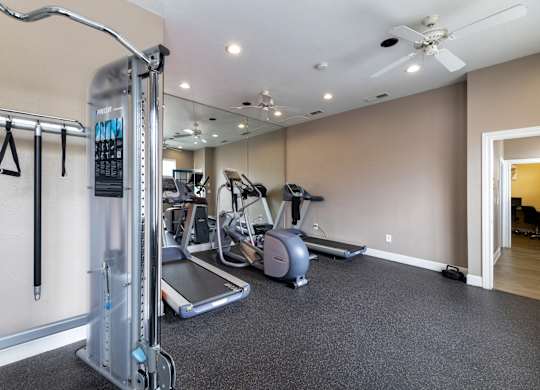 A gym with a treadmill, elliptical machines, and other exercise equipment.