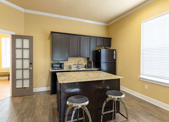 A kitchen with a bar stool in front of a counter.
