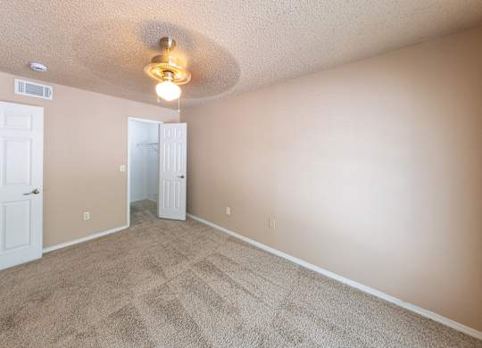 A room with a carpeted floor and a ceiling fan.