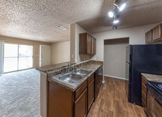 A kitchen with a black refrigerator and wooden cabinets.