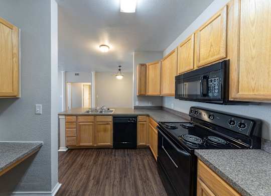 A kitchen with wooden cabinets and black appliances.