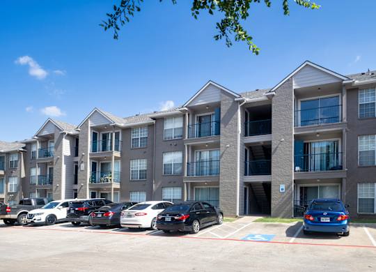 A parking lot with cars and apartment buildings in the background.
