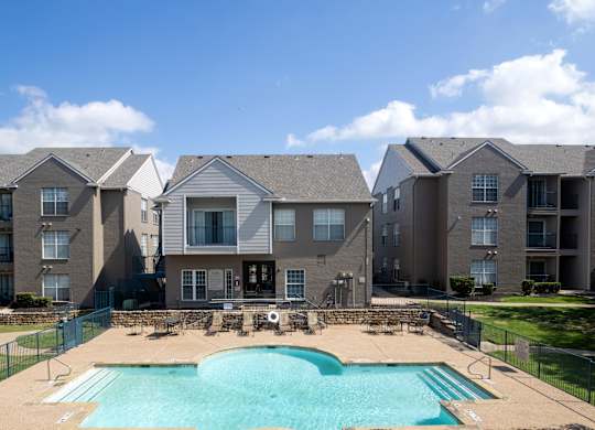 A large swimming pool in front of apartment buildings.