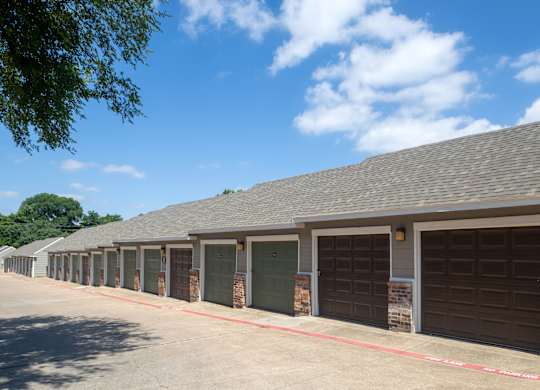 A long building with a grey roof and brown garage doors.
