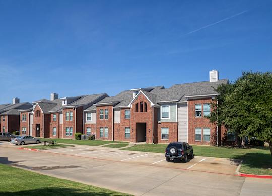 A row of red brick houses with a black car parked in front of the first house.
