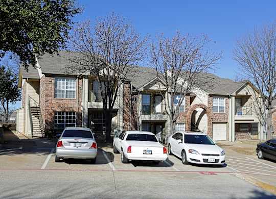 A white car is parked in front of a brick building.