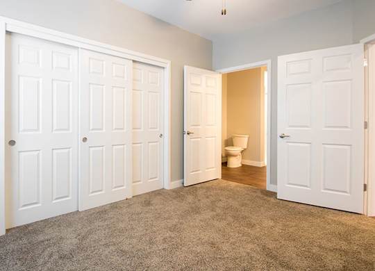 A room with white doors and a carpeted floor.