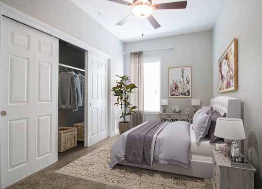 A bedroom with a bed, nightstand, and a ceiling fan.