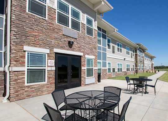 A patio with a table and chairs is in front of a brick building.