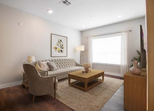 A living room with a grey couch, a wooden coffee table, and a painting on the wall.