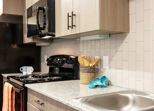 A kitchen with a black stove and a black microwave above it.