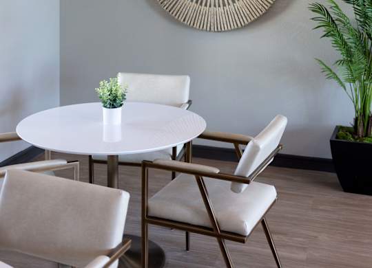A white table with four chairs and a plant in a pot.
