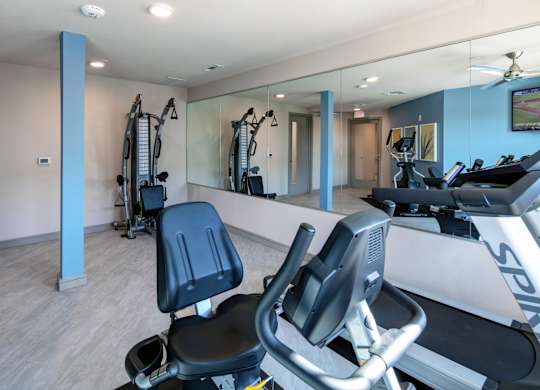 A gym with a treadmill and mirrors.