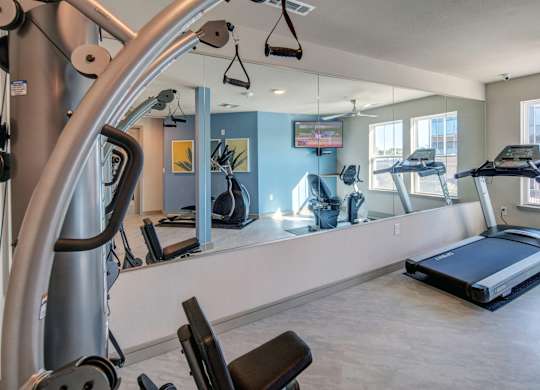 A gym with a treadmill, elliptical machines, and other exercise equipment.