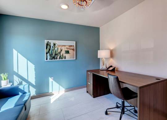 A room with a blue wall and a wooden desk with a chair.