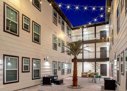 A courtyard with a palm tree and a balcony.