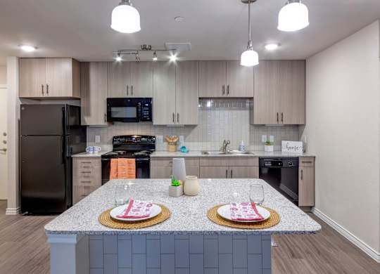 A kitchen with a black refrigerator and a granite countertop.