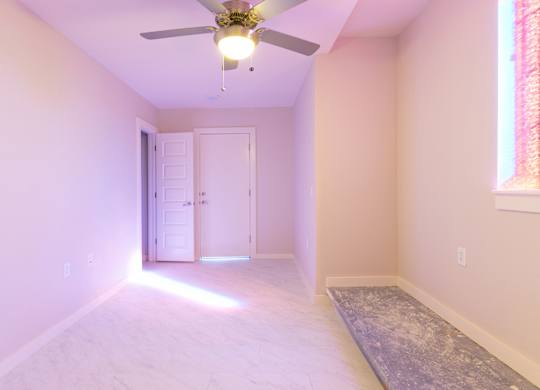 A room with a ceiling fan and a light on.