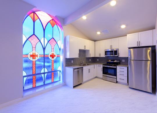 A kitchen with a stained glass window and white cabinets.