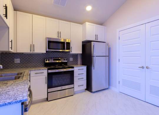 A kitchen with white cabinets and appliances.