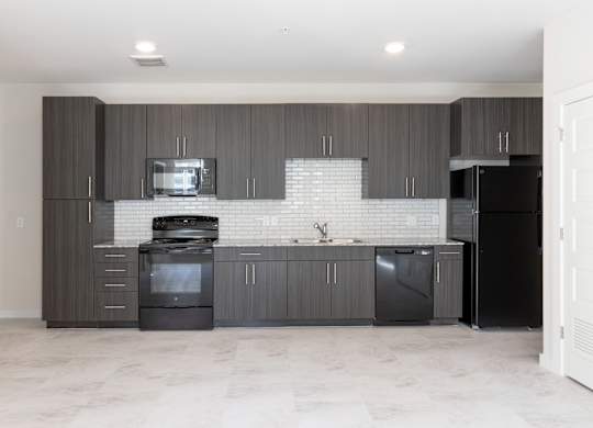 A modern kitchen with dark wood cabinets and black appliances.