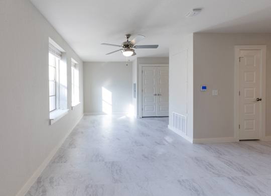 A spacious room with a ceiling fan and marble flooring.