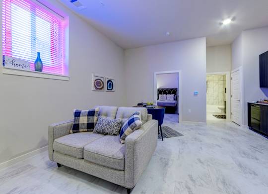 A living room with a couch and a window with blinds.