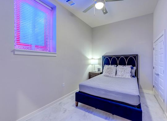 A bedroom with a bed, pillows, and a ceiling fan.