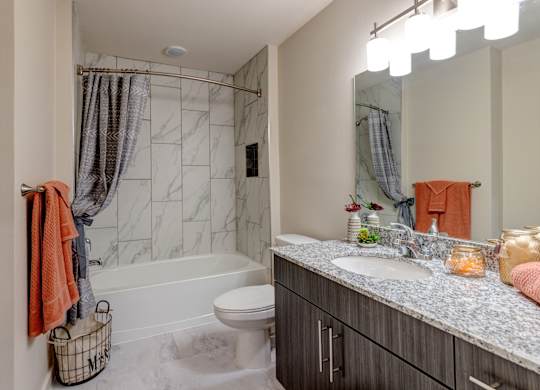 A bathroom with a marble tile shower and a white toilet.
