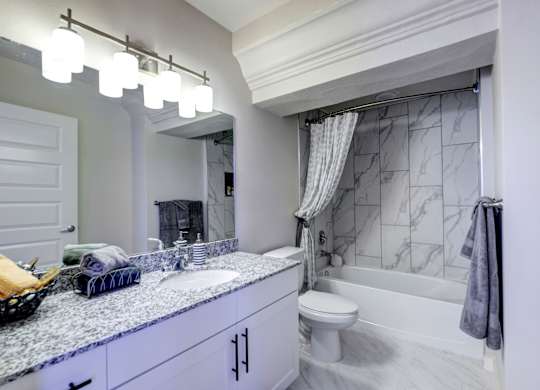 A bathroom with a marble countertop and a white toilet.