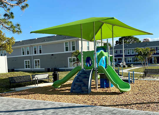 A playground with a green slide and a green canopy.