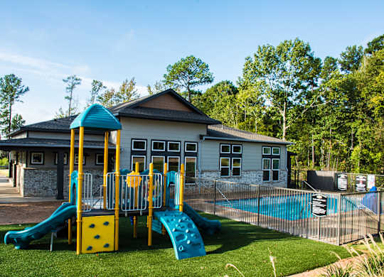 A playground with a yellow and blue slide in front of a building.