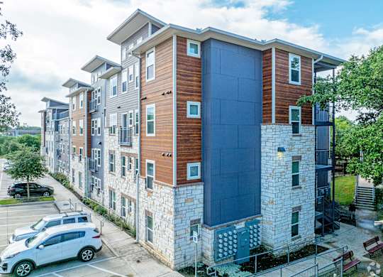 A modern apartment building with a parking lot in front.