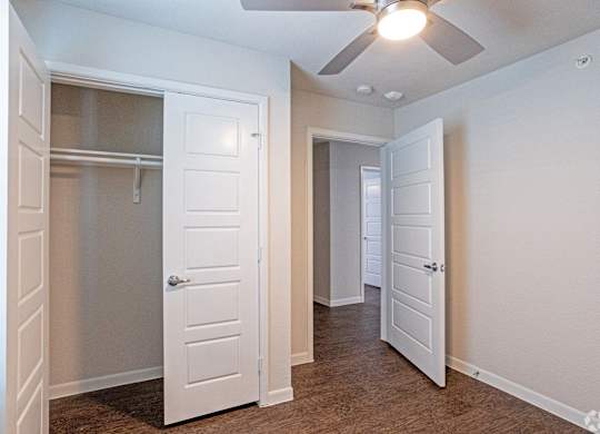 A room with a ceiling fan and two doors.