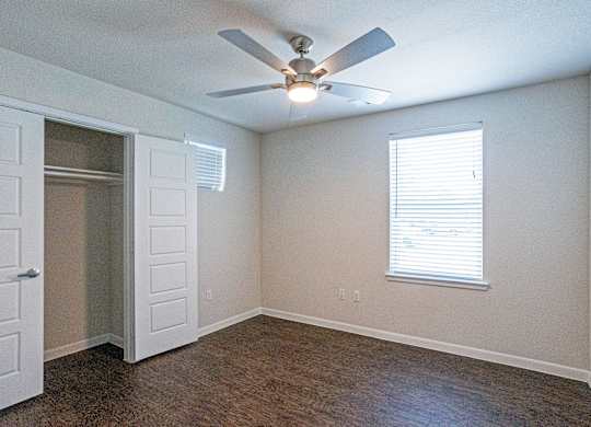 A room with a ceiling fan and a window with blinds.