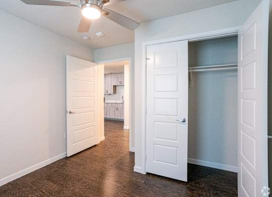 A room with a ceiling fan and two doors.